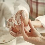 A close-up of hands preparing dough, emphasizing family teamwork.