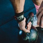 Muscular athlete lifting kettlebell during workout session, showcasing strength and fitness.